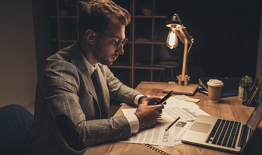 young-businessman-using-smartphone-at-workplace-on-FCWHU4Q